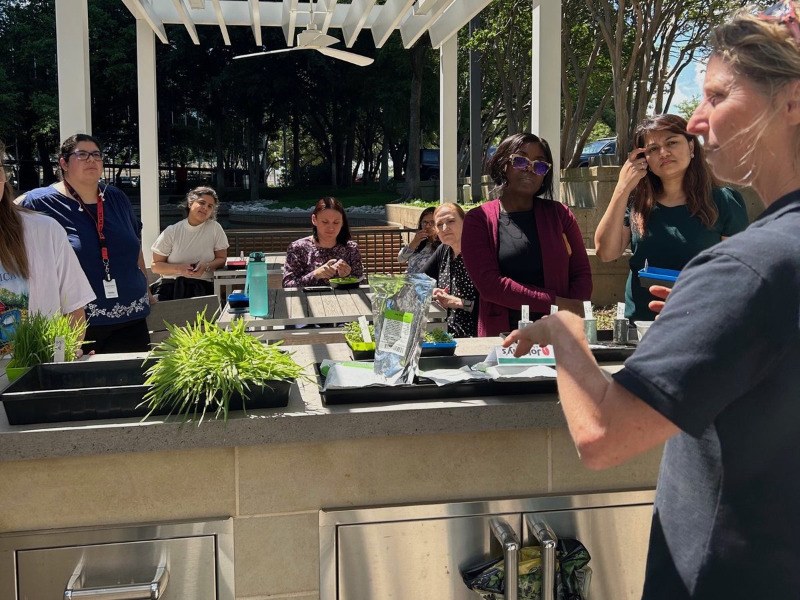 Piper teaching a hands-on microgreens class under a pergola